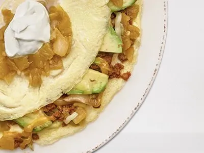 First Watch Chile Chorizo Omelet - fluffy omelet filled with chorizo, avocado, green chiles, house-roasted onions, and Cheddar and Monterey Jack cheese.
