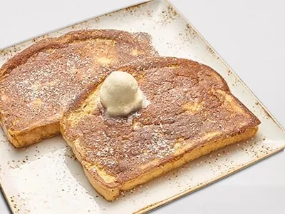 First Watch French Toast - custard-dipped, thick-cut brioche bread topped with whipped butter, powdered cinnamon sugar, and warm mixed berry compote.