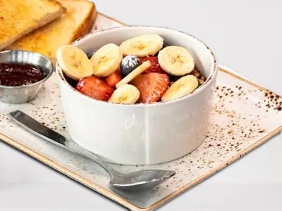 Kids Granola Bowl from First Watch, featuring non-fat vanilla Greek yogurt topped with housemade granola, almonds, bananas, strawberries, blueberries, and a sprinkle of powdered cinnamon sugar.