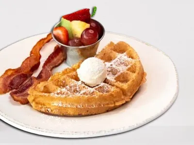 Half Waffle from First Watch, featuring a fluffy Belgian waffle served with fresh seasonal fruit and your choice of bacon or sausage.