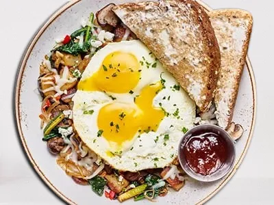 First Watch Market Hash - two cage-free eggs atop seasoned potatoes, house-roasted Crimini mushrooms, zucchini, shallots, red peppers, baby spinach, Mozzarella, and herbed Goat cheese.