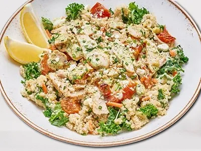 Pesto Chicken Quinoa Bowl from First Watch, featuring quinoa, kale, shredded carrots, house-roasted tomatoes, grilled chicken, basil pesto sauce, and Feta cheese.