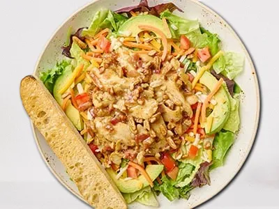 Sweet Honey Pecan Salad from First Watch, featuring organic mixed greens, romaine lettuce, all-natural chicken breast, crispy bacon, toasted pecans, avocado, tomatoes, shredded carrots, and Cheddar and Monterey Jack cheeses, drizzled with warm honey Dijon dressing.