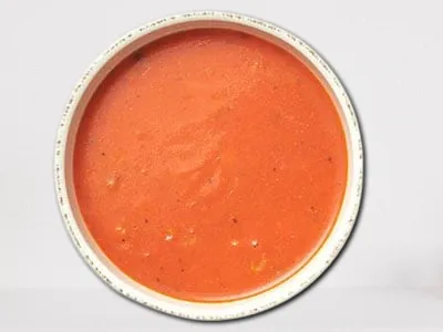 Tomato Basil Soup from First Watch, featuring a creamy blend of fire-roasted tomatoes, fresh basil, and a touch of cream, served with a sprinkle of Parmesan cheese.